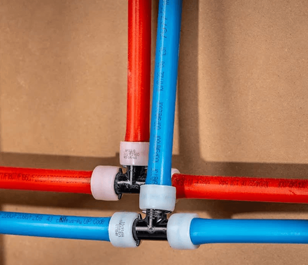 Red and blue PEX pipes connected with black T-fittings and white expansion rings.
